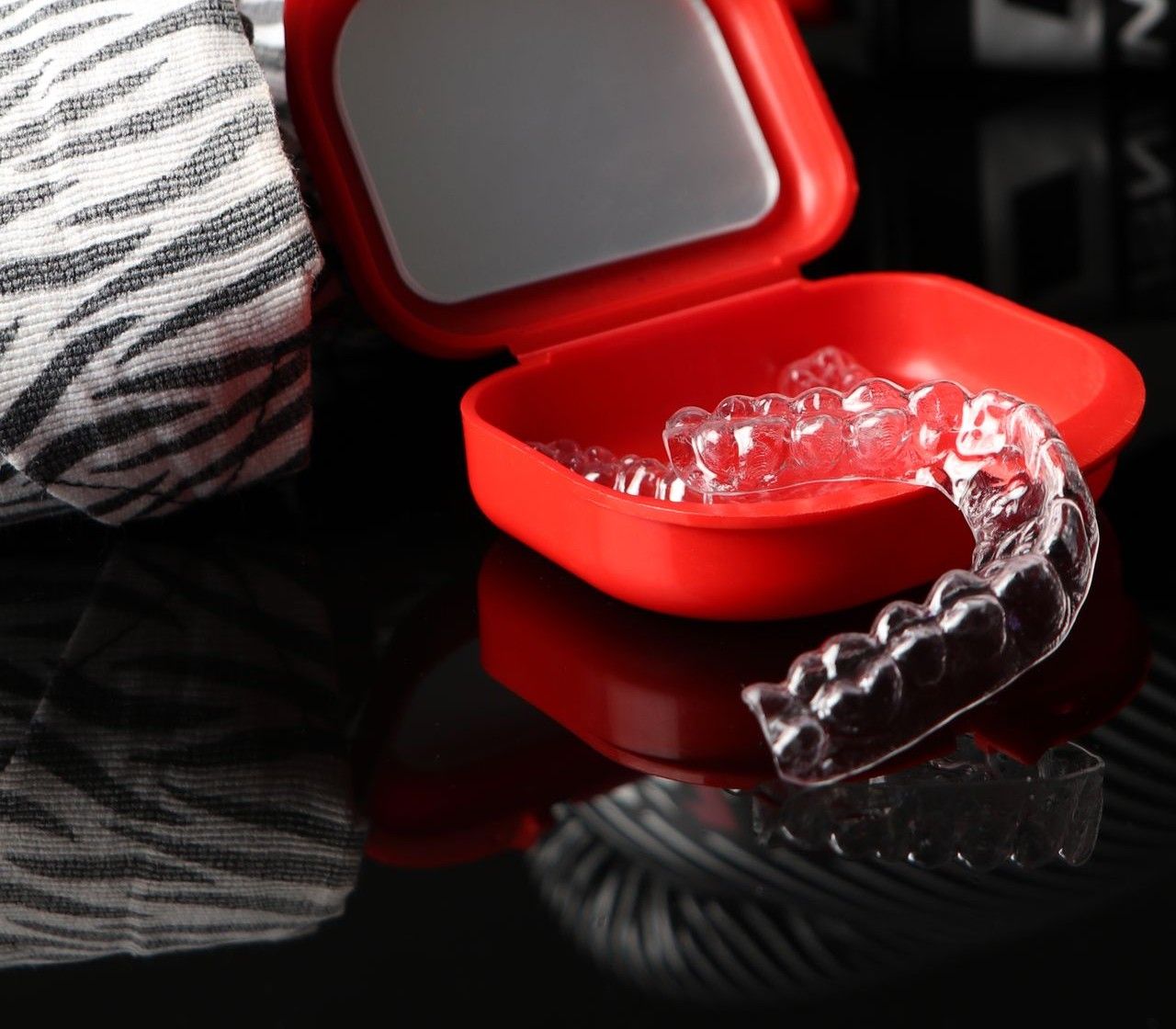 A clear custom sports mouthguard in a red storage case.
