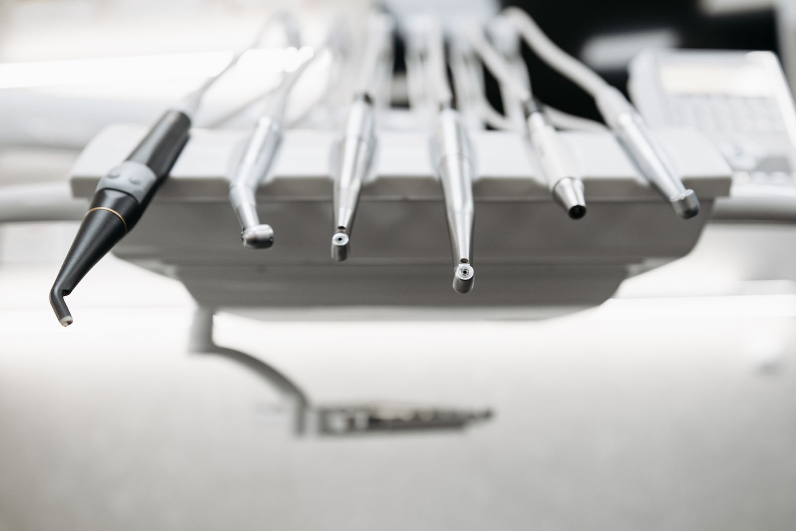 Polished dental handpieces and instruments resting on a clinic delivery tray.