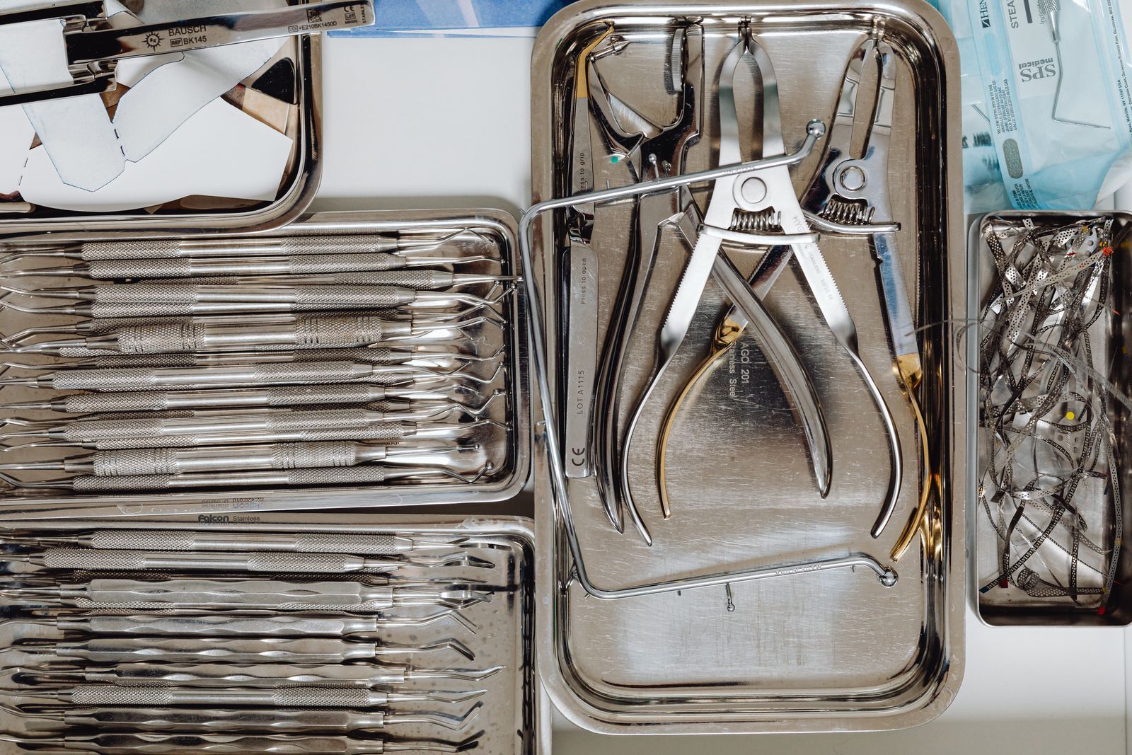 Sterilized stainless dental instruments arranged in metal trays.