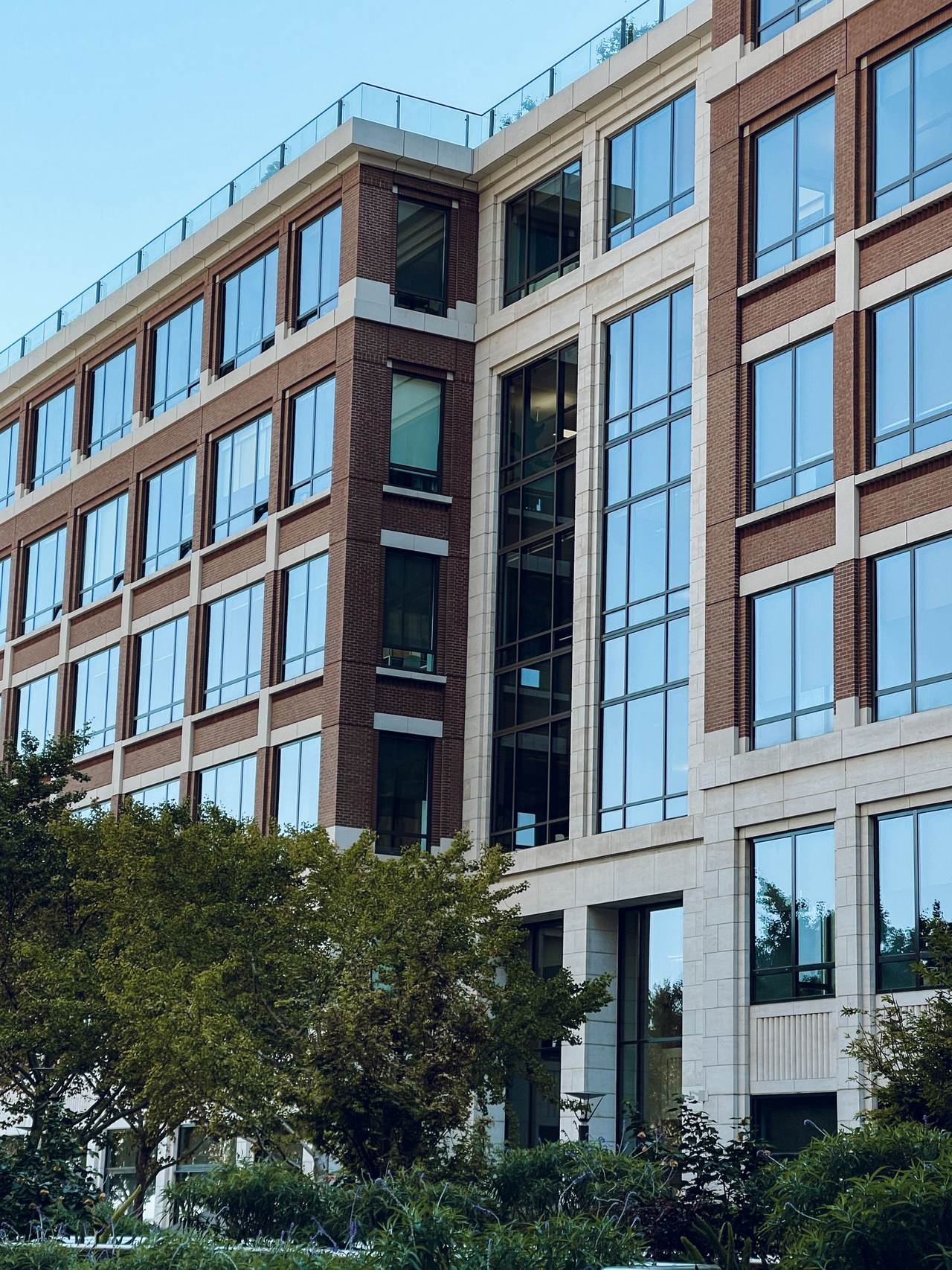 A modern low-rise brick and glass professional building with trees in front.